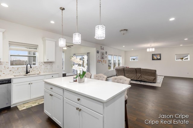 kitchen featuring stainless steel dishwasher, plenty of natural light, open floor plan, and a sink