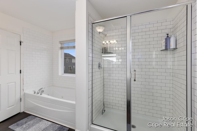 bathroom featuring a shower stall, a bath, and wood finished floors