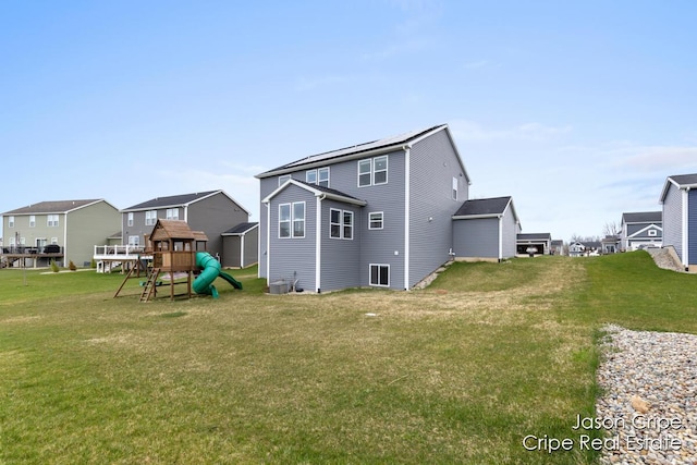 back of property with a yard, a playground, and central air condition unit