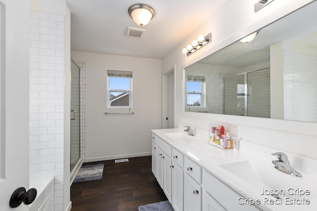 full bath with visible vents, wood finished floors, a sink, a stall shower, and baseboards