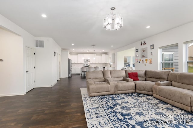 living area featuring dark wood finished floors, visible vents, recessed lighting, baseboards, and a notable chandelier