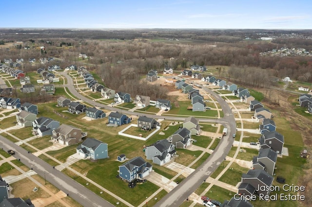 drone / aerial view featuring a wooded view and a residential view