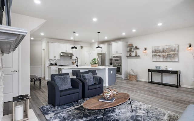 living room with baseboards, light wood-type flooring, and recessed lighting