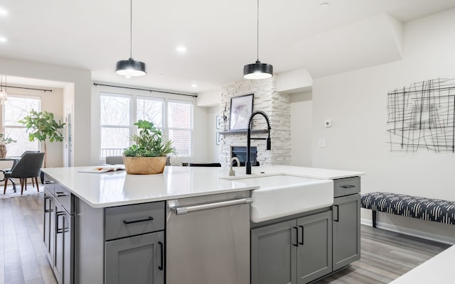 kitchen with light countertops, dishwasher, a sink, gray cabinetry, and light wood-style flooring