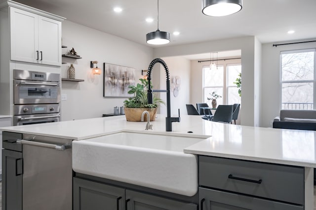 kitchen with light countertops, gray cabinets, recessed lighting, and a sink