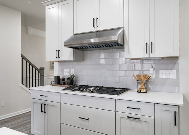 kitchen featuring stainless steel gas stovetop, decorative backsplash, light countertops, and under cabinet range hood