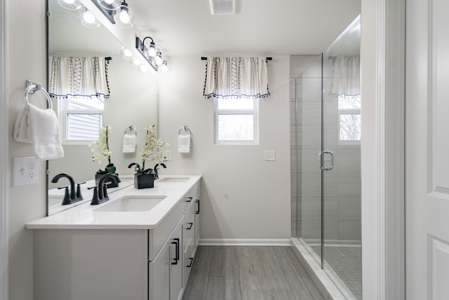 bathroom with a shower stall, wood finished floors, a sink, and visible vents