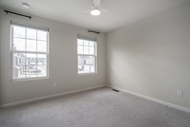 unfurnished room featuring visible vents, a ceiling fan, baseboards, and light colored carpet