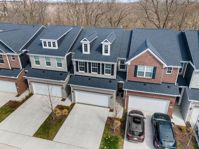 multi unit property with brick siding, an attached garage, concrete driveway, and roof with shingles