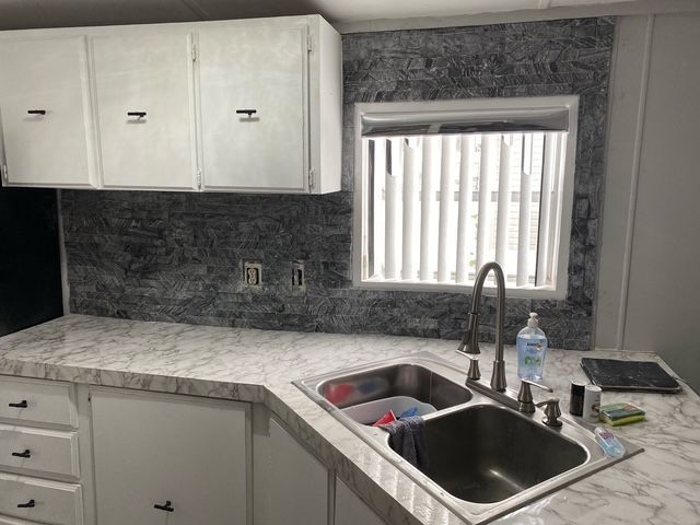 50594 Oregon Ave, Novi, MI 48374 - kitchen with light countertops, decorative backsplash, a sink, and white cabinets