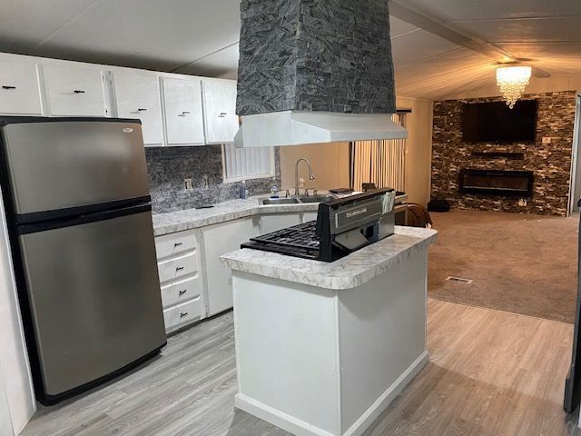 50594 Oregon Ave, Novi, MI 48374 - kitchen with light wood-style flooring, light countertops, freestanding refrigerator, white cabinetry, and a sink