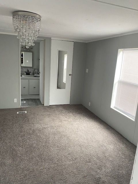 50594 Oregon Ave, Novi, MI 48374 - carpeted empty room with ornamental molding and an inviting chandelier