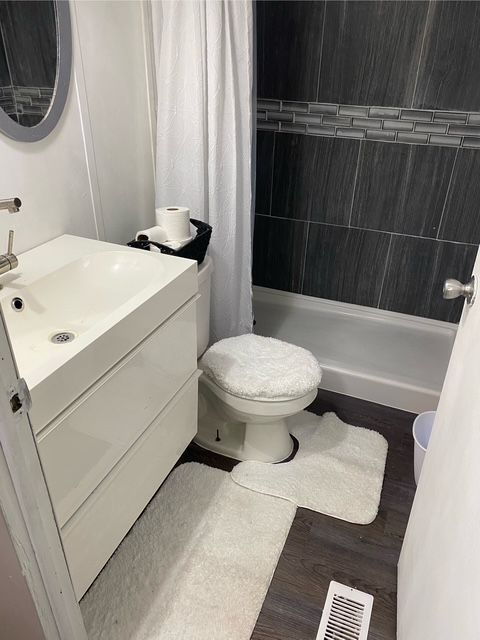 50594 Oregon Ave, Novi, MI 48374 - bathroom featuring a tile shower, wood finished floors, vanity, and toilet
