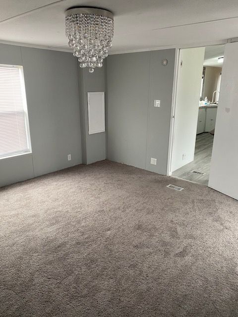 50594 Oregon Ave, Novi, MI 48374 - carpeted empty room featuring visible vents, an inviting chandelier, and crown molding