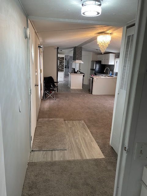 50594 Oregon Ave, Novi, MI 48374 - hallway featuring carpet flooring, a sink, and an inviting chandelier