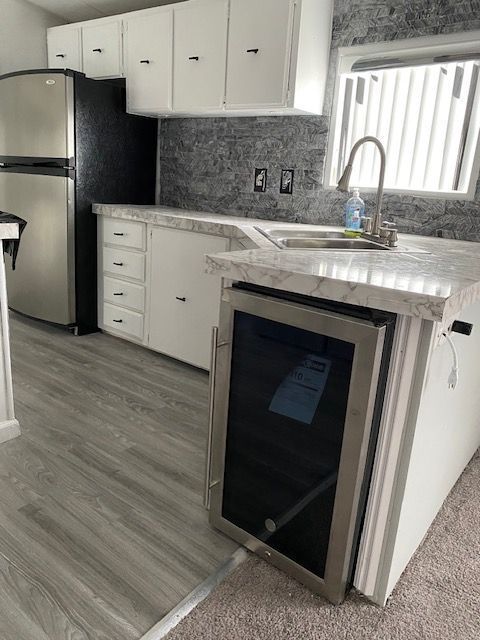 50594 Oregon Ave, Novi, MI 48374 - kitchen with freestanding refrigerator, a sink, white cabinetry, and wine cooler