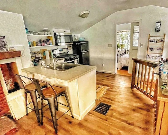 520 Bellevue Ave, Lake Orion, MI 48362 - kitchen featuring light wood-style floors, a kitchen bar, lofted ceiling, appliances with stainless steel finishes, and visible vents