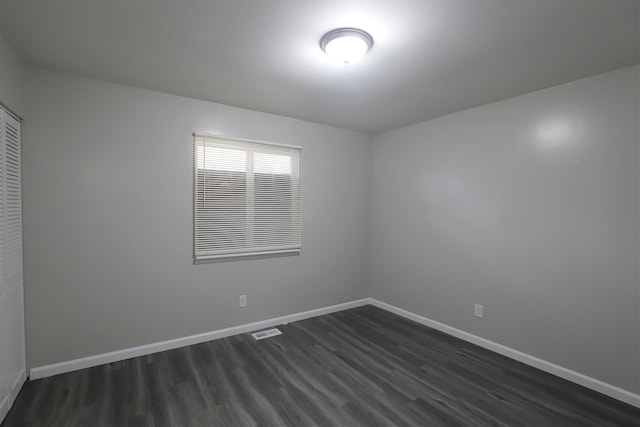 spare room with visible vents, baseboards, and dark wood-style floors