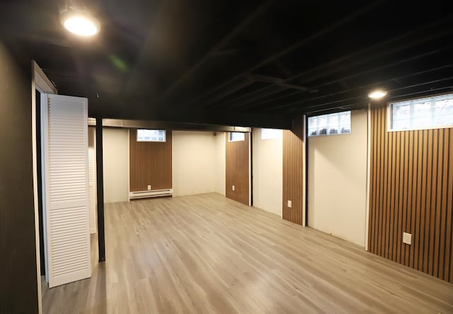 below grade area featuring a baseboard radiator and wood finished floors