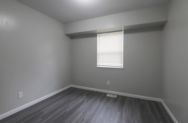 spare room with baseboards, visible vents, and dark wood-style floors