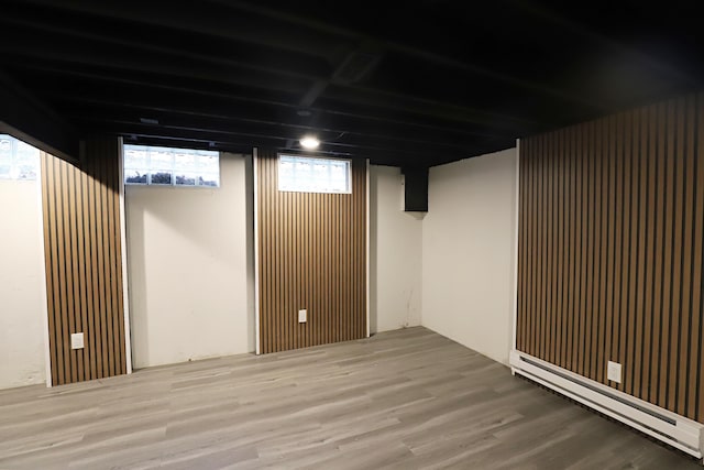 below grade area featuring a baseboard heating unit and wood finished floors