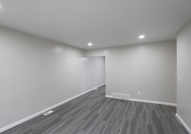 finished below grade area with dark wood-type flooring, visible vents, and baseboards
