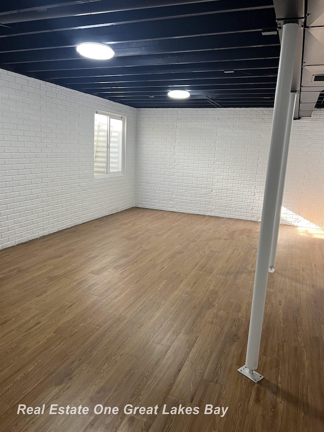 basement with brick wall and wood finished floors