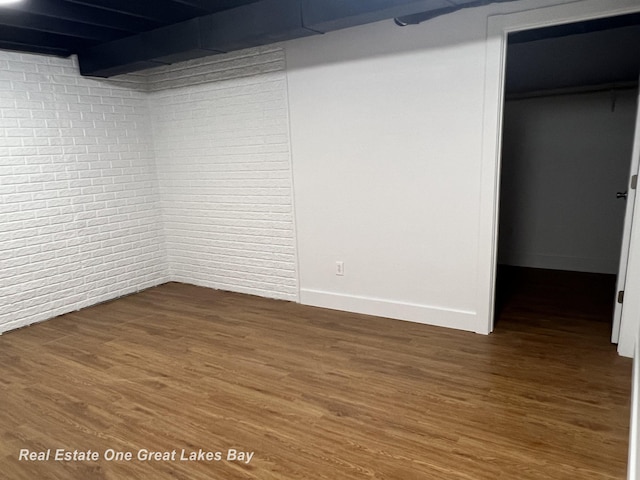 finished basement featuring wood finished floors and brick wall