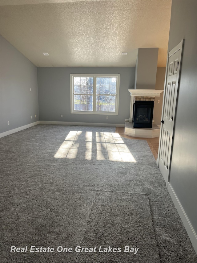 8311 Goldfinch Rd, Freeland, MI 48623 - unfurnished living room featuring carpet floors, a textured ceiling, and a glass covered fireplace