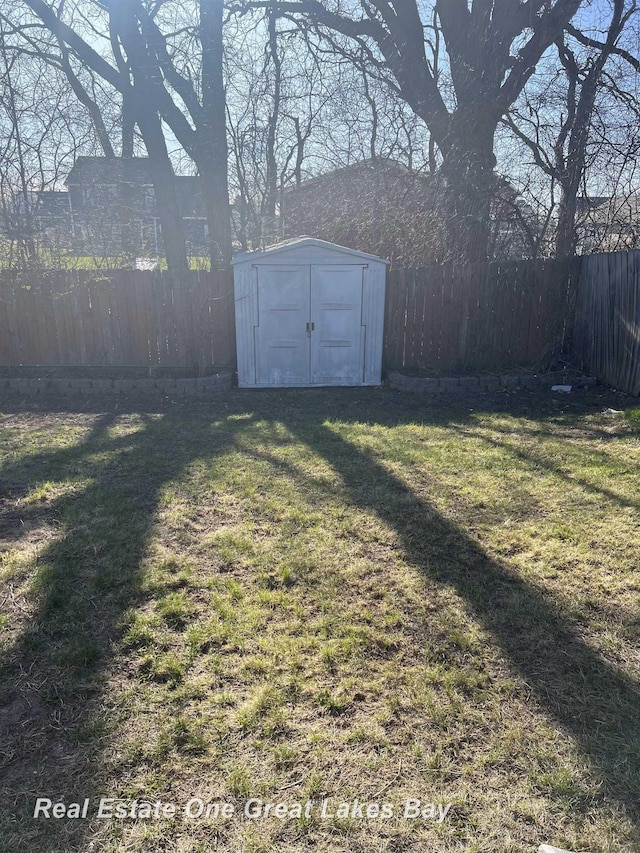view of yard featuring a fenced backyard, an outdoor structure, and a shed