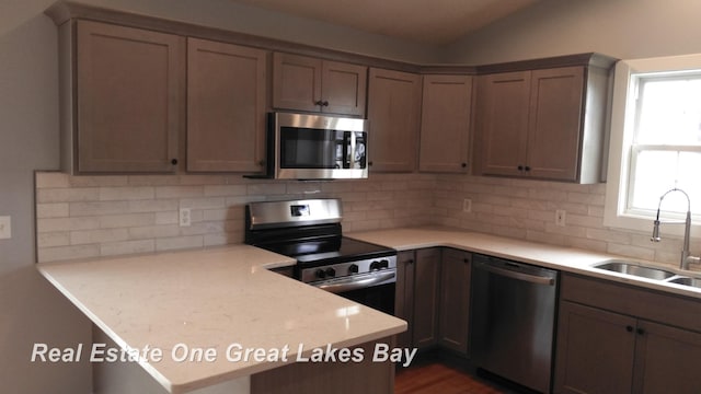 8311 Goldfinch Rd, Freeland, MI 48623 - kitchen featuring appliances with stainless steel finishes, a peninsula, light countertops, and tasteful backsplash