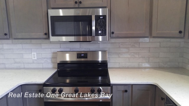 8311 Goldfinch Rd, Freeland, MI 48623 - kitchen featuring appliances with stainless steel finishes, decorative backsplash, and light stone counters