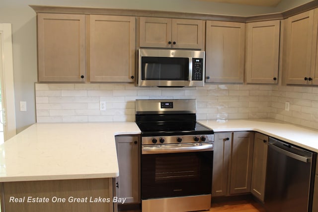 8311 Goldfinch Rd, Freeland, MI 48623 - kitchen featuring stainless steel appliances, decorative backsplash, and a peninsula