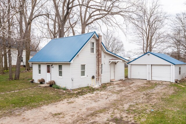 327 E Main St, Vermontville, MI 49096 - view of side of home with a detached garage, a chimney, metal roof, an outdoor structure, and a yard
