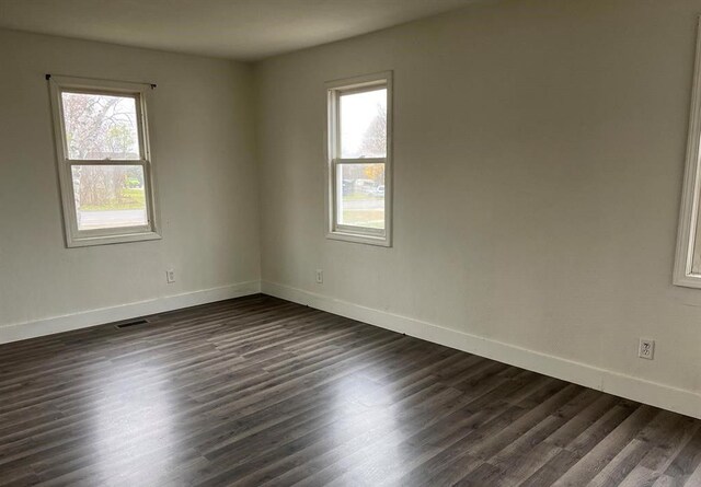 327 E Main St, Vermontville, MI 49096 - unfurnished room with visible vents, baseboards, dark wood-type flooring, and a healthy amount of sunlight