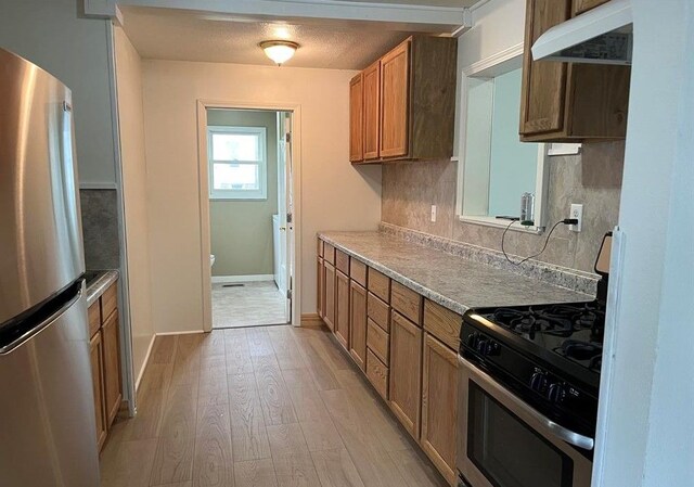 327 E Main St, Vermontville, MI 49096 - kitchen with extractor fan, decorative backsplash, brown cabinets, light wood-type flooring, and appliances with stainless steel finishes