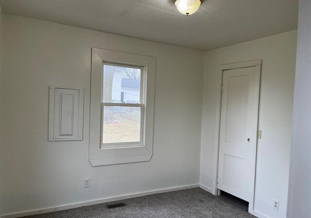 327 E Main St, Vermontville, MI 49096 - unfurnished room featuring baseboards, dark colored carpet, and visible vents