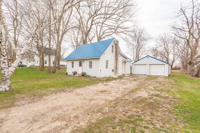 327 E Main St, Vermontville, MI 49096 - view of side of property featuring an outbuilding, a yard, a detached garage, and metal roof