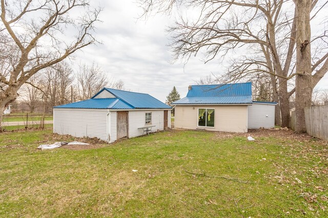 327 E Main St, Vermontville, MI 49096 - back of property with fence, a lawn, an outbuilding, and metal roof