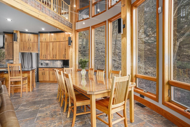 dining space featuring visible vents, baseboards, recessed lighting, stone finish floor, and a high ceiling