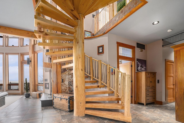 staircase featuring a towering ceiling and recessed lighting