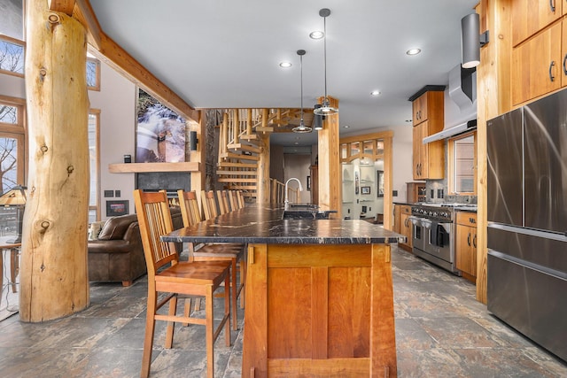 kitchen with stone finish floor, dark countertops, appliances with stainless steel finishes, and a breakfast bar area