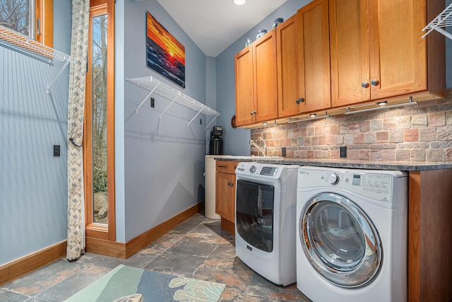 laundry room featuring baseboards, washer and dryer, cabinet space, and stone finish flooring