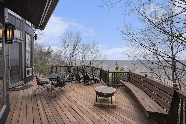 wooden terrace with a water view and outdoor dining space
