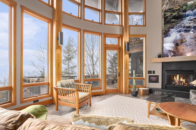 interior space featuring a healthy amount of sunlight, a towering ceiling, and a large fireplace