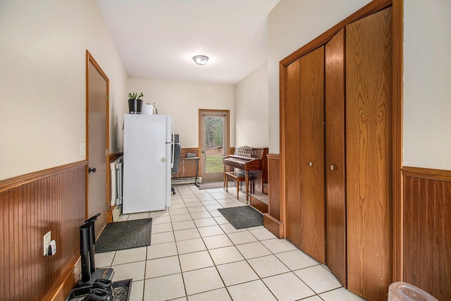 corridor featuring light tile patterned floors, wainscoting, and wooden walls