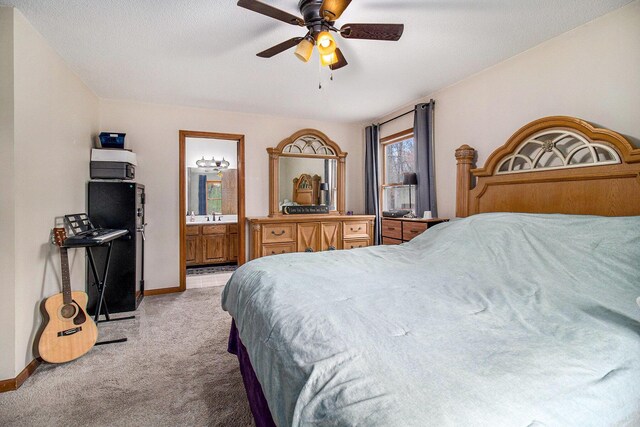 bedroom featuring baseboards, light carpet, ensuite bath, ceiling fan, and a sink