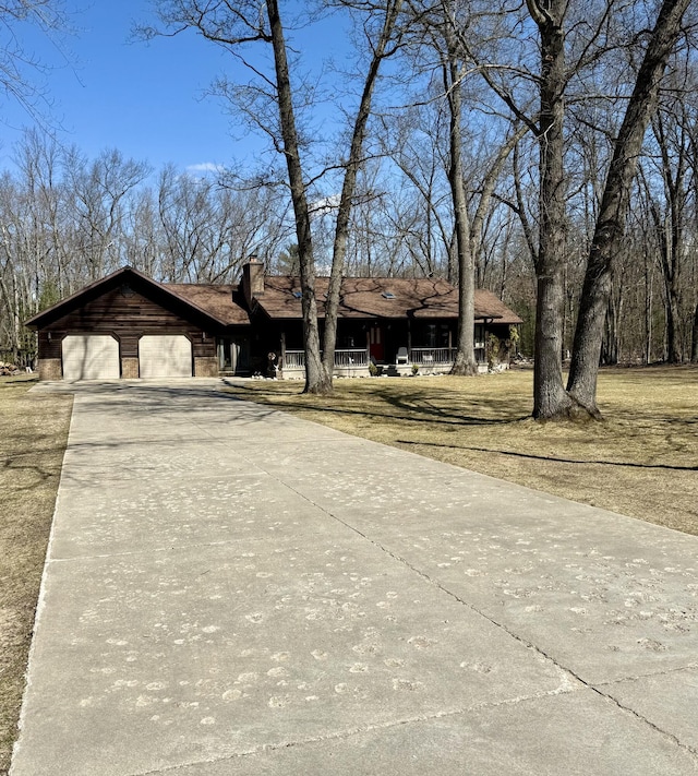ranch-style home featuring an attached garage, a chimney, concrete driveway, and a front lawn