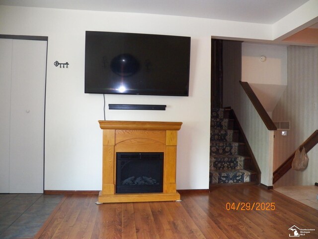 7303 Cranbrook Dr, Lambertville, MI 48144 - unfurnished living room with baseboards, a glass covered fireplace, wood finished floors, and stairway