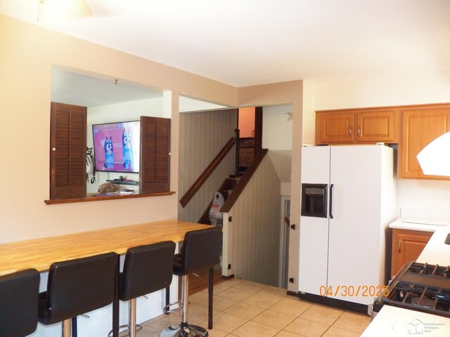 7303 Cranbrook Dr, Lambertville, MI 48144 - kitchen featuring brown cabinetry, light tile patterned floors, white refrigerator with ice dispenser, and range hood